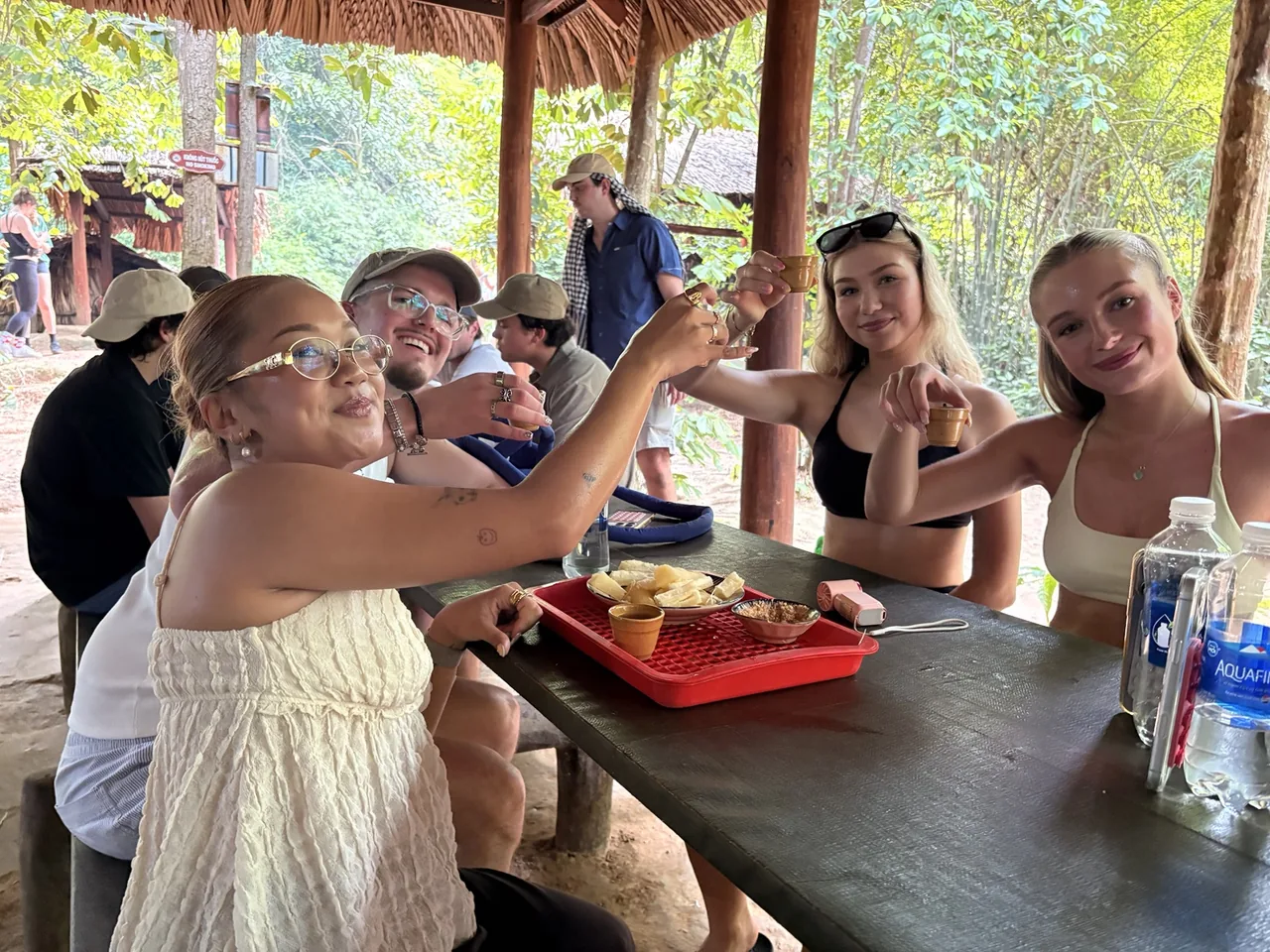 OG Saigon guests raising cups of tea together during a cassava break at Cu Chi