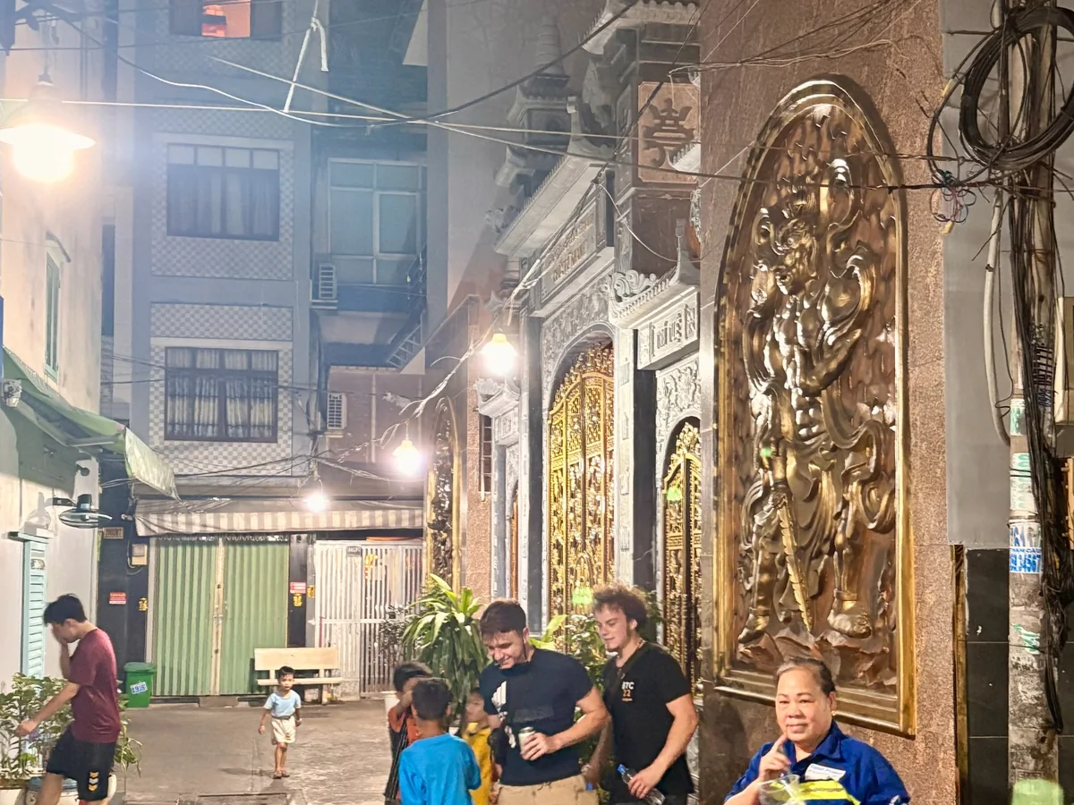 Residents, children and visitors sharing a narrow District 4 alley at night
