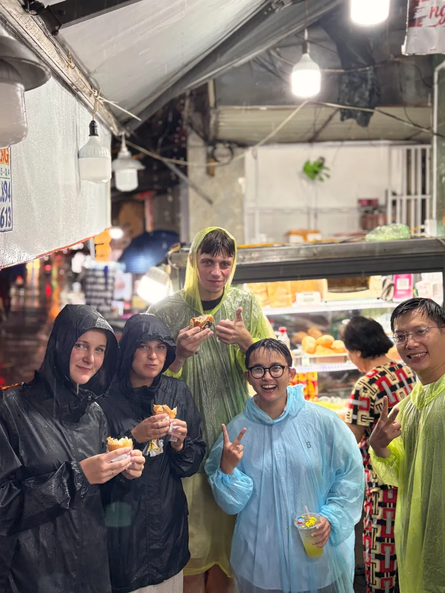 OG Saigon guests eating bánh mì with local hosts during a rainy evening