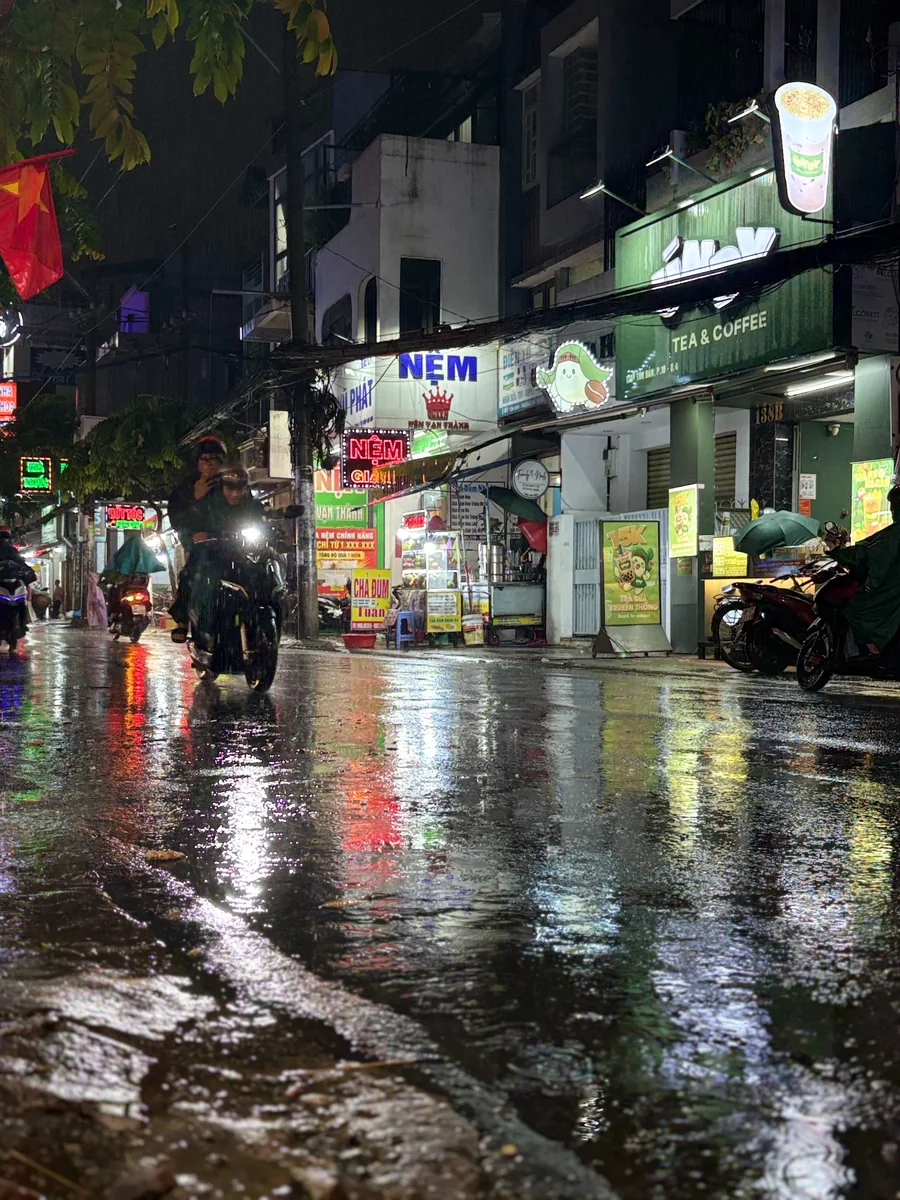 Rainy Saigon street at night with motorbikes and reflections