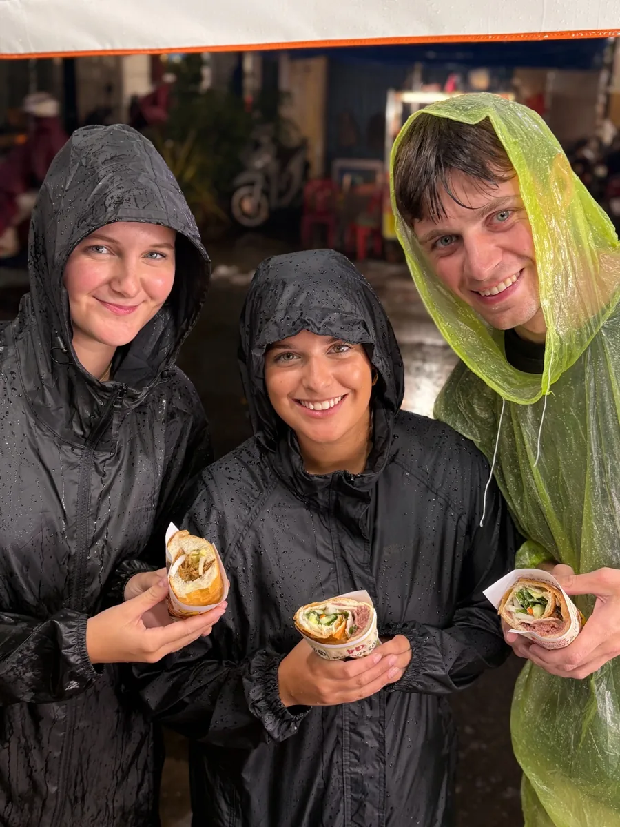 Guests eating bánh mì during a rainy OG Saigon street-food evening